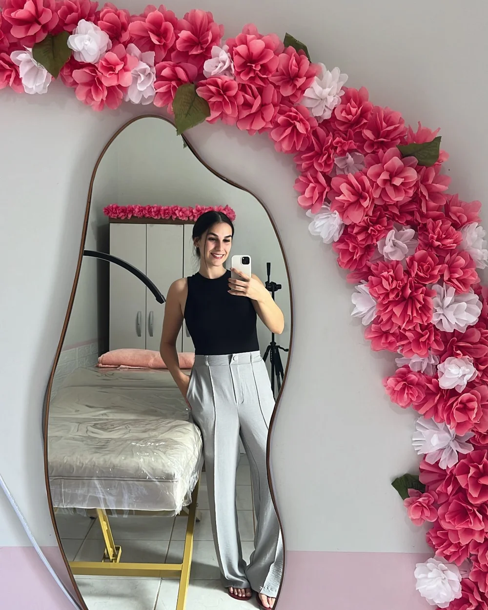 Luana no espelho do studio, com o arco de flores rosa e brancas